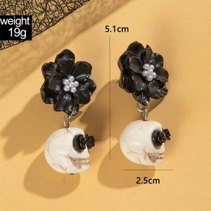 Macro detail of gothic skull and black camellia earrings with size and weight specs
