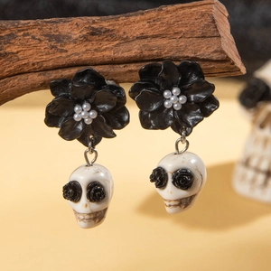 Gothic black camellia and white skull drop earrings with pearl detail on a wooden branch