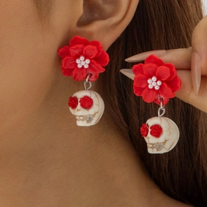 Macro shot of Halloween punk earrings featuring red 3D roses, pearls and skull charms