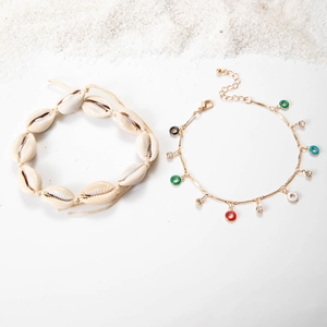 Detailed view of bohemian shell anklet and colorful enamel beads on a sandy beach background