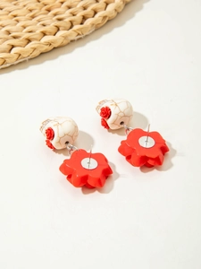 Macro view of gothic skull and red camellia floral earrings with pearl punk details