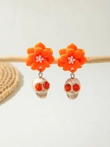 Detail of Day of the Dead earrings with orange flowers and skull charms on wood