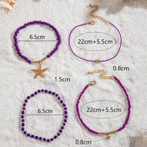 Detail of bohemian purple beaded anklet set with starfish charm on white sand background