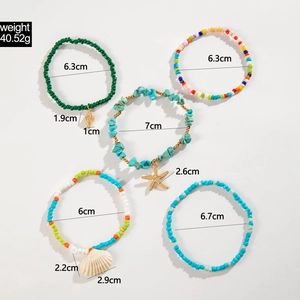 Detail view of 5-piece bohemian anklet set with starfish and shell charms on white background