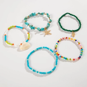 Detail of bohemian starfish and shell charms on colorful beaded anklet set for summer