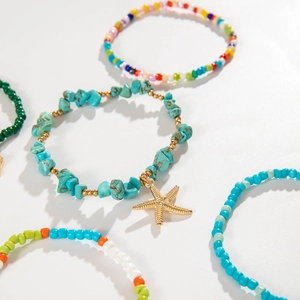 Detail of bohemian starfish charms and colorful seed bead anklets set on a white background