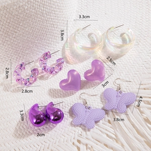 Lot de dix paires de boucles d'oreilles cœur et papillon violettes sur fond paille