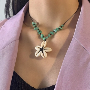 Detail of bohemian necklace with handmade seashell flower and green crushed stones