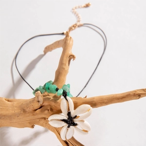 Detail of bohemian shell necklace with white flower pendant and green stone beads