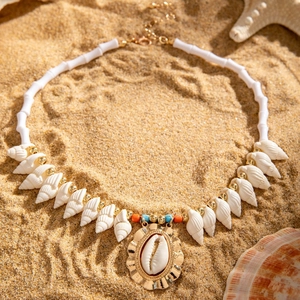 Detail of seashell beach necklace with starfish and golden accents on warm sand