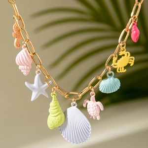 Macro detail of gold chain necklace featuring colorful marine pendants like starfish and shells