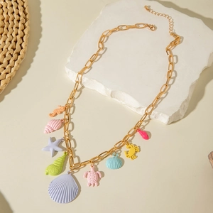 Detail view of gold chunky chain necklace with colorful marine life charms on stone