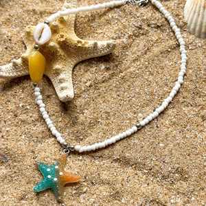 Bohemian beaded necklace with shell, starfish and stone pendant on sandy beach