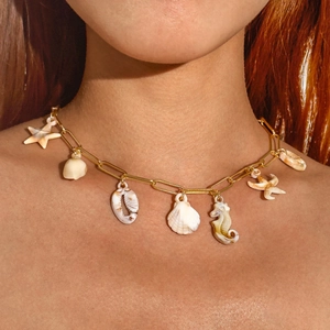 Detail of bohemian gold chain necklace with starfish and seashell pendants on skin