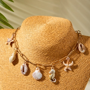 Detail of bohemian gold paperclip necklace with shell and starfish charms on woven stand