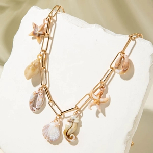 Detail of golden paperclip chain necklace with starfish, seashell, and seahorse charms
