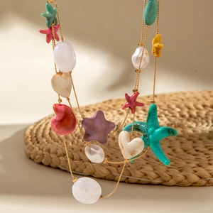 Detail of bohemian gold layered necklace with colorful starfish and white shell pearls