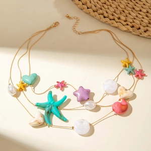 Close-up of bohemian starfish pendants and pastel heart charms on golden multi-layer necklace