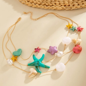Detail showing layers of gold chains with colorful starfish charms and pearl accents