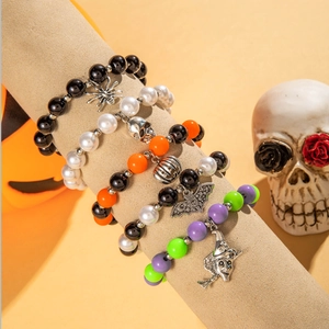 Detail of five Halloween stretch beaded bracelets featuring skull and bat charms on a stand