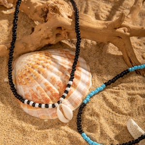 Détail du collier de plage bohème avec perles colorées et coquillage sur le sable