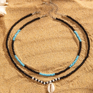 Détail d'un collier bohème multicouche avec perles colorées et coquillage sur sable