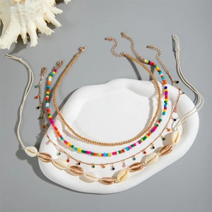 Gros plan d'un ensemble de colliers bohèmes superposés avec coquillages et perles