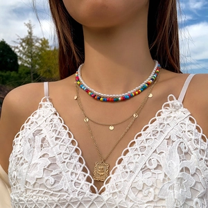 Détail du collier bohème multicouche avec perles colorées, perles nacrées et pendentif doré