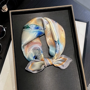 Close-up of silk square scarf featuring artistic oil painting prints on a display tray