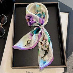 Detail of silk scarf with purple floral ink patterns and a decorative pearl buckle