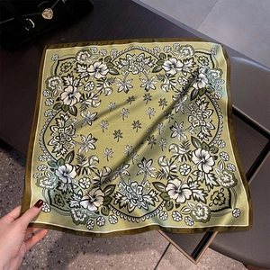 Nahaufnahme von olivgrünem Seidenschal mit tropischem Blumenmuster und feiner Nahtverarbeitung