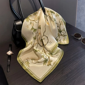 Detail eines Seidenschals an Ledertasche mit französischem Vintage-Olivenrebenmuster