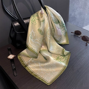 Detail of silk scarf with sea coral print draped over a black leather handbag