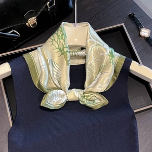 Elegant silk scarf with coral and shell print tied on a hanger with blue vest