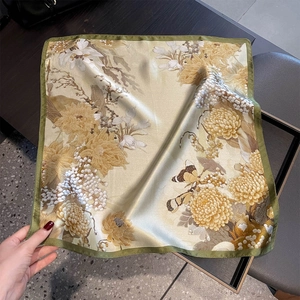 Detailed macro view of a silk square scarf with floral butterfly prints and green borders