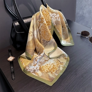 Detail of floral silk square scarf with chrysanthemum print on a fashion handbag