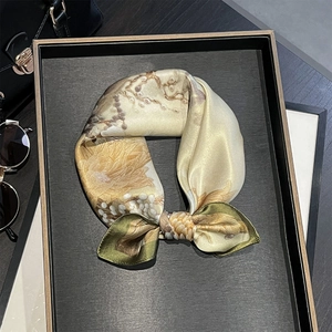 Detailed view of floral silk scarf tied in a bow on a luxury display tray