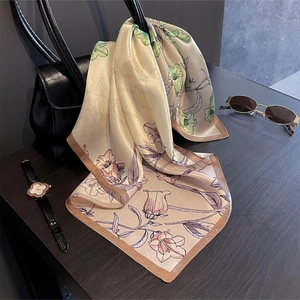 Floral print silk square scarf in champagne gold draped over a black handbag