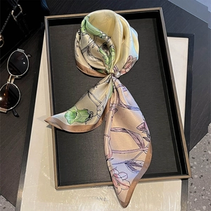 Detail of floral silk twilly scarf with a pearl metal ring buckle on a black tray
