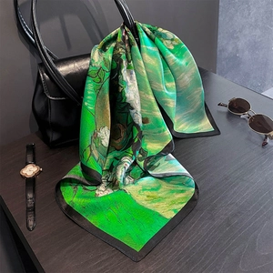 Détail d'un foulard en soie aux motifs artistiques noué sur un sac à main noir