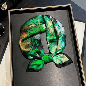 Détail d'un foulard en soie style peinture à l'huile avec imprimé vert et bord noir