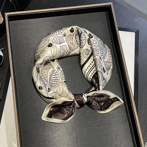 Détail d'un foulard en soie de 53 cm aux motifs de coquillages et d'étoiles de mer noué