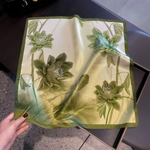 Détail de foulard en soie vert clair avec motif lotus et bordure roulée de précision