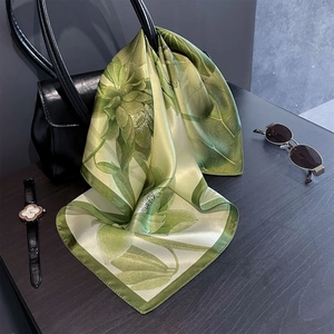 Détail d'un foulard en soie à motif lotus drapé sur un sac à main en cuir noir