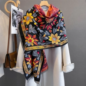 Floral print winter scarf with sunflower motifs and fringe details on a wool coat