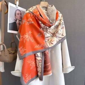 Detail of floral print autumn scarf with frayed edges draped on a white winter coat