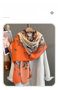 Dettaglio di sciarpa in finta cashmere con stampa farfalla e frange eleganti