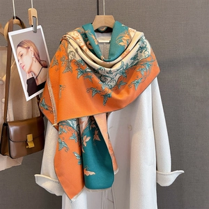 Dettaglio di sciarpa con motivo floreale vintage e frange su un cappotto di cashmere