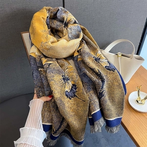 Détail d'une écharpe à fleurs et papillons vintage avec des bords à pompons épais