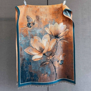 Gros plan d'une écharpe en jacquard floral aux motifs rétro orange et bleu à franges